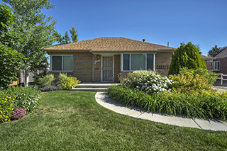 The front exterior of a one-story brown house with a beautiful front yard, similar to a single-family home that could be receiving expert Denver property management from Walters and Company Property Management 